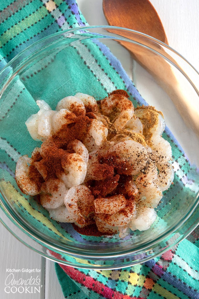 adding seasonings to shrimp in mixing bowl