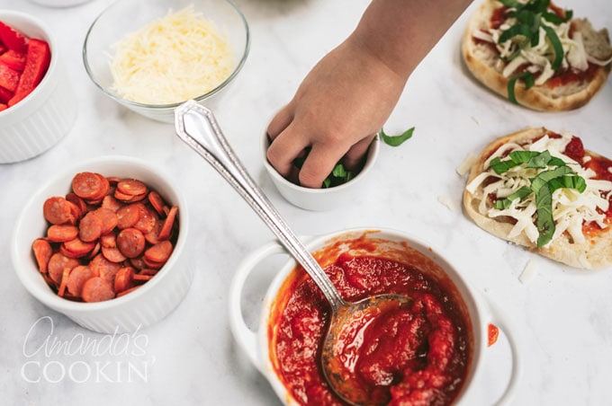 small child's hand taking basil from a bowl