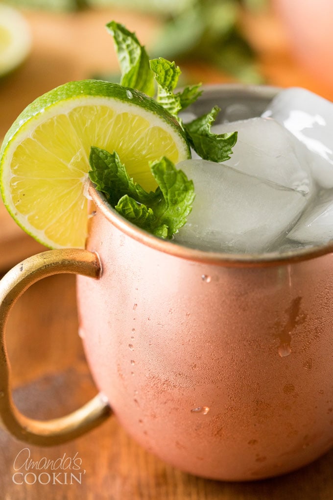 close up photo of moscow mule with lime and mint garnish in copper mug