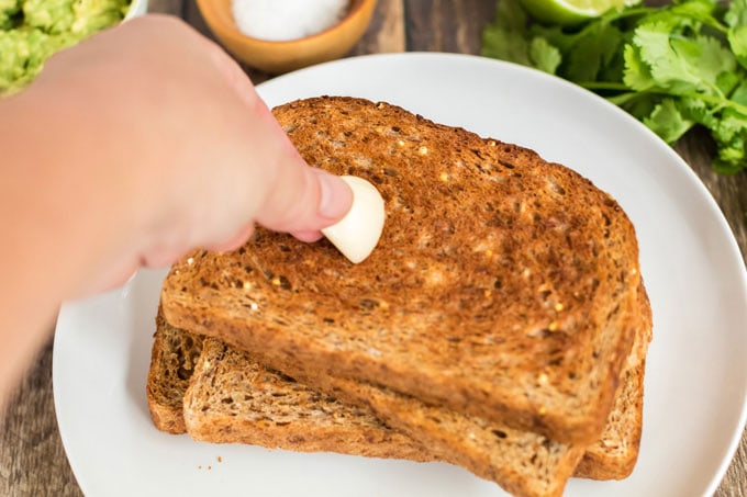 rubbing toast with a garlic clove