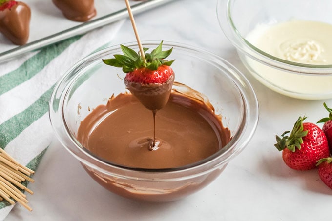 dipping a strawberry into melted chocolate