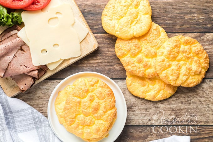 several pieces of cloud bread with a cutting board of cheese and lunch meat