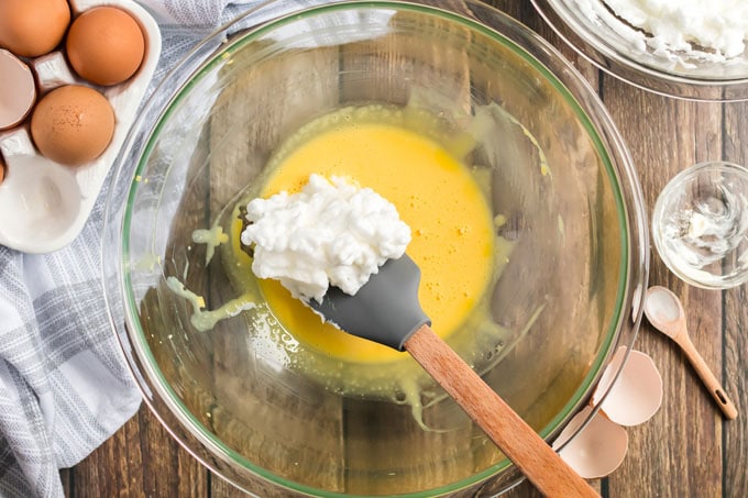 adding whipped egg white to yolk mixture in bowl