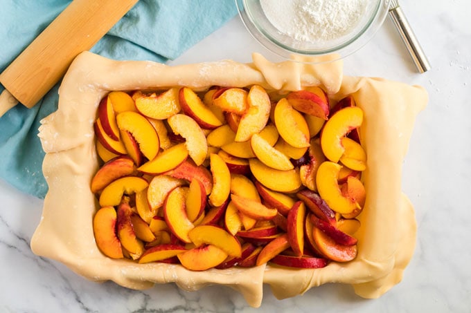 sliced peaches in pie dough in pan