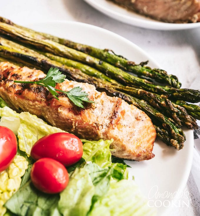 grilled salmon steak on a plate with grilled asparagus and salad