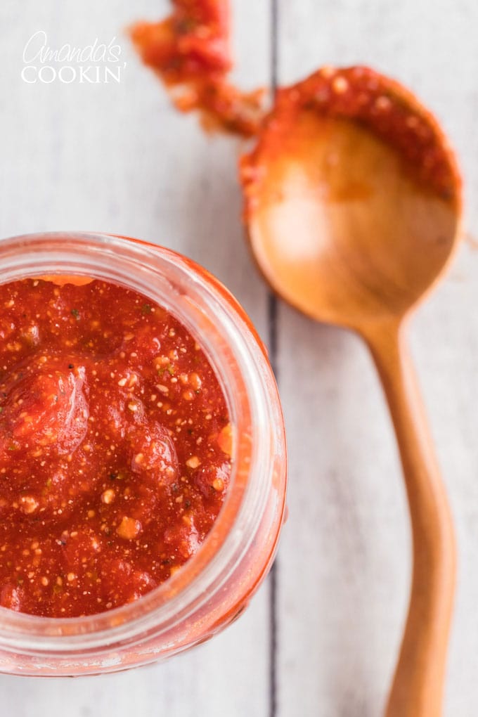 close up of jar of homemade pizza sauce with a spoon on the side