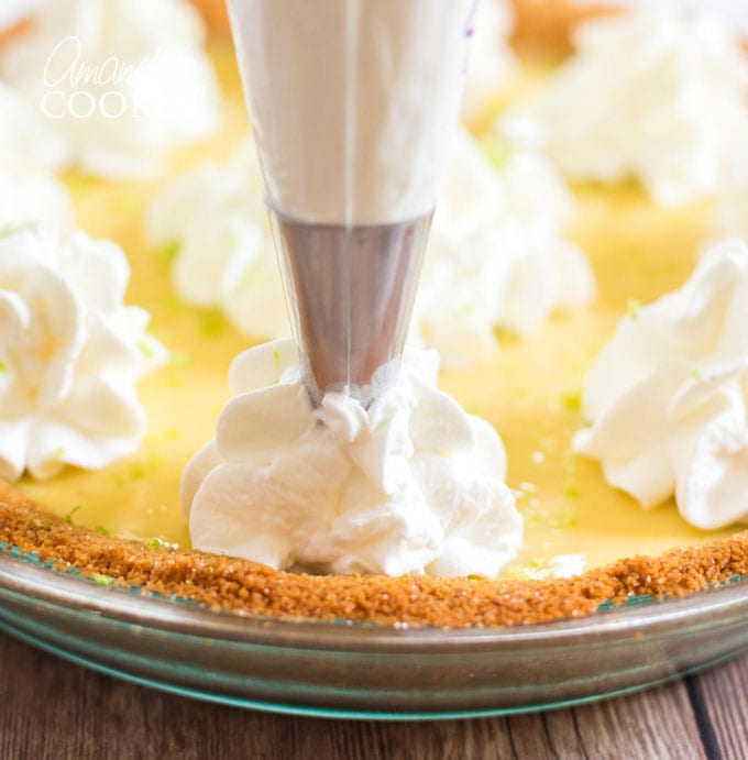 piping whipped cream on to key lime pie