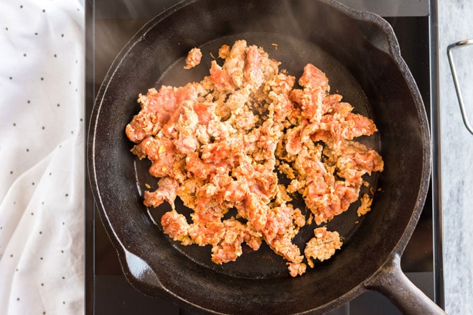 ground pork sausage being browned in a cast iron skillet