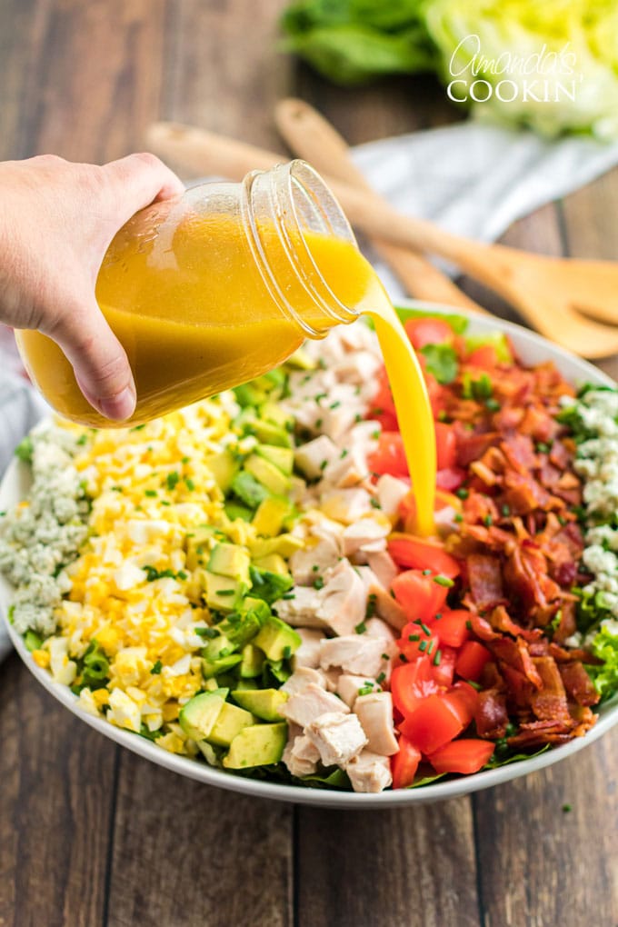 pouring dressing over cobb salad