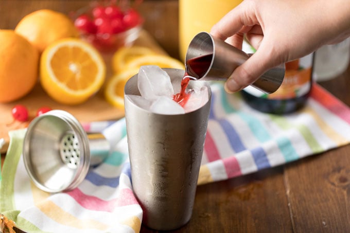 adding cranberry juice to cocktail shaker