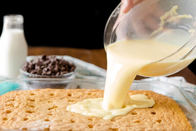 pouring thin pudding over cake with holes in it