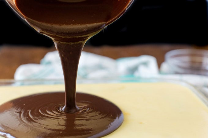 pouring chocolate over pudding layer on cake