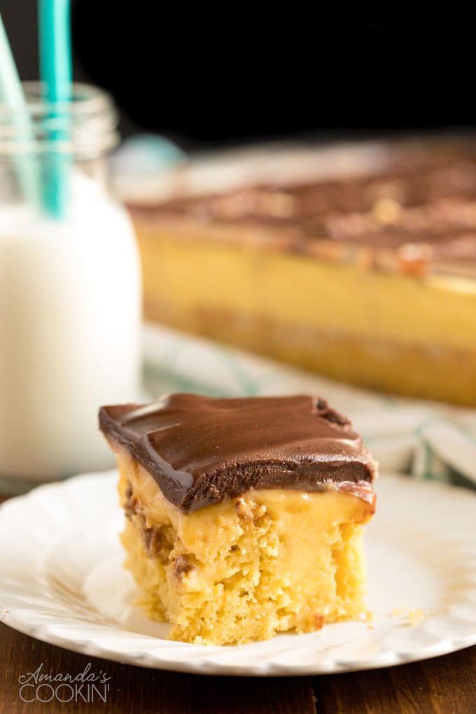 slice of boston cream poke cake on a white plate with bottle of milk in background