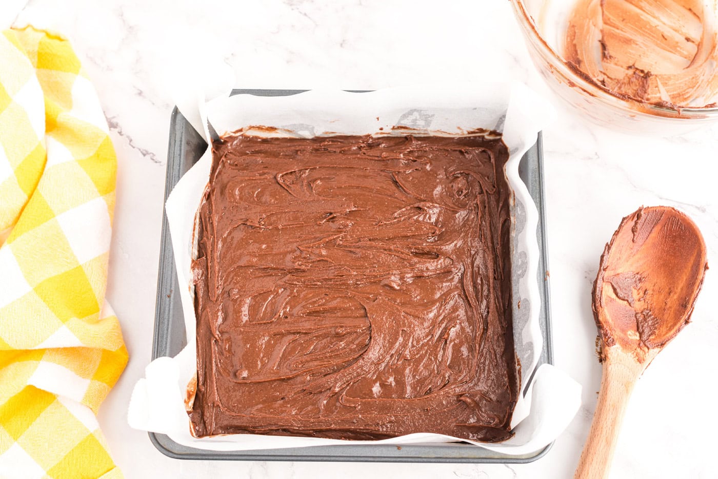 brownie batter in a parchment lined square pan