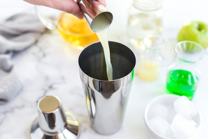 pouring lemon juice into a cocktail shaker