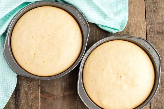 two round cake pans with baked white cake