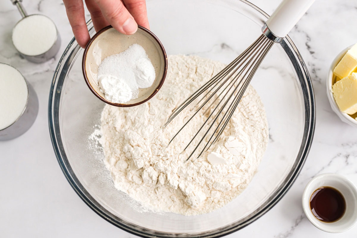 whisking flour and baking powder in a bowl with a whisk