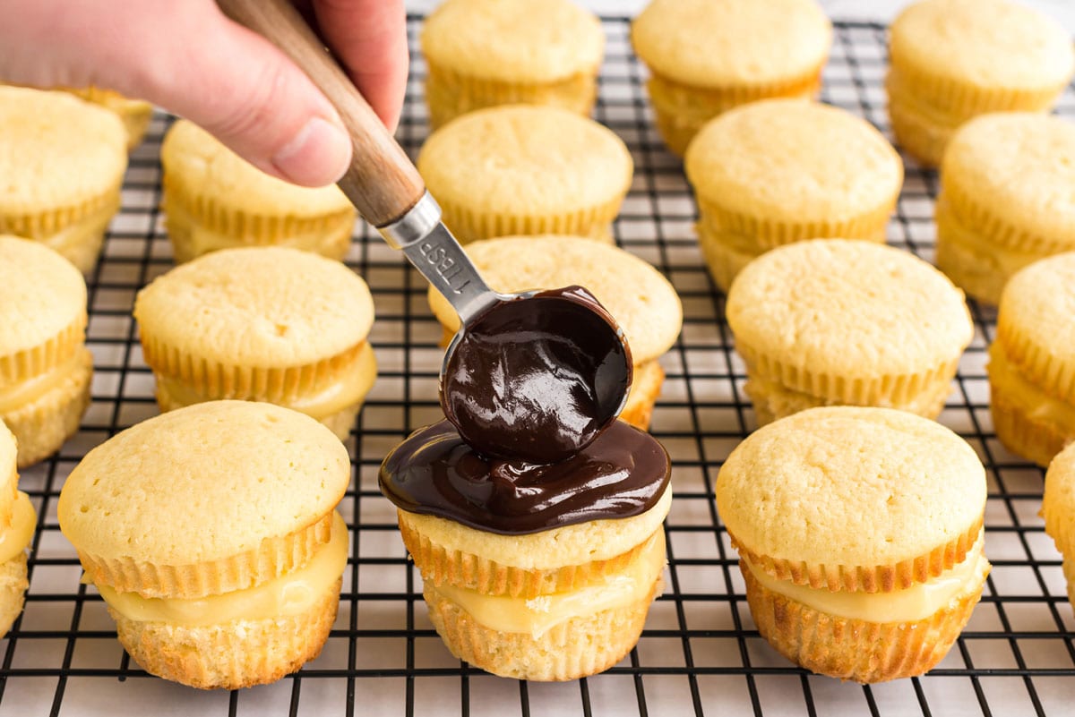 spreading ganache on top of cupcake with back of a spoon