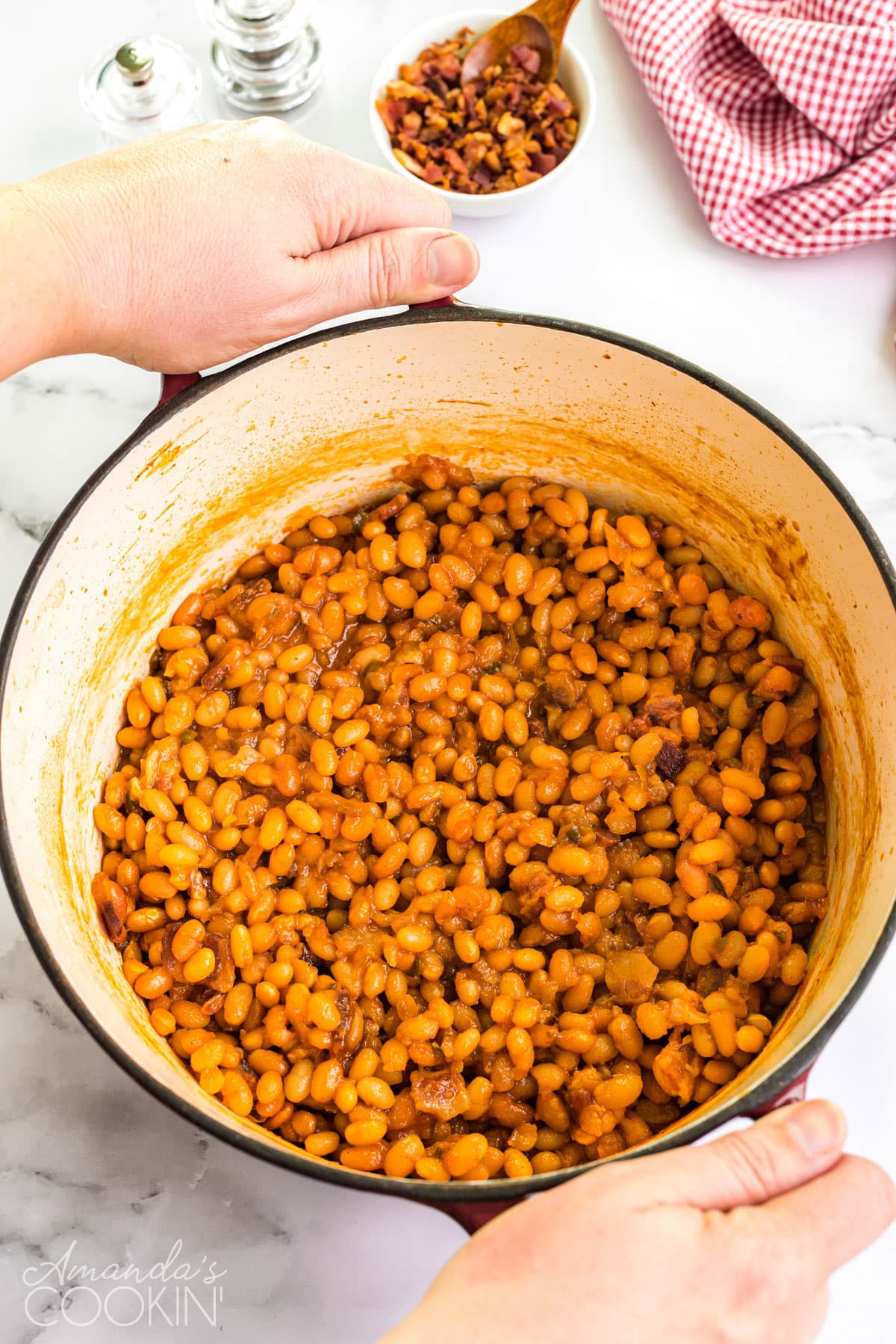 dutch oven full of homemade baked beans being carried to the table