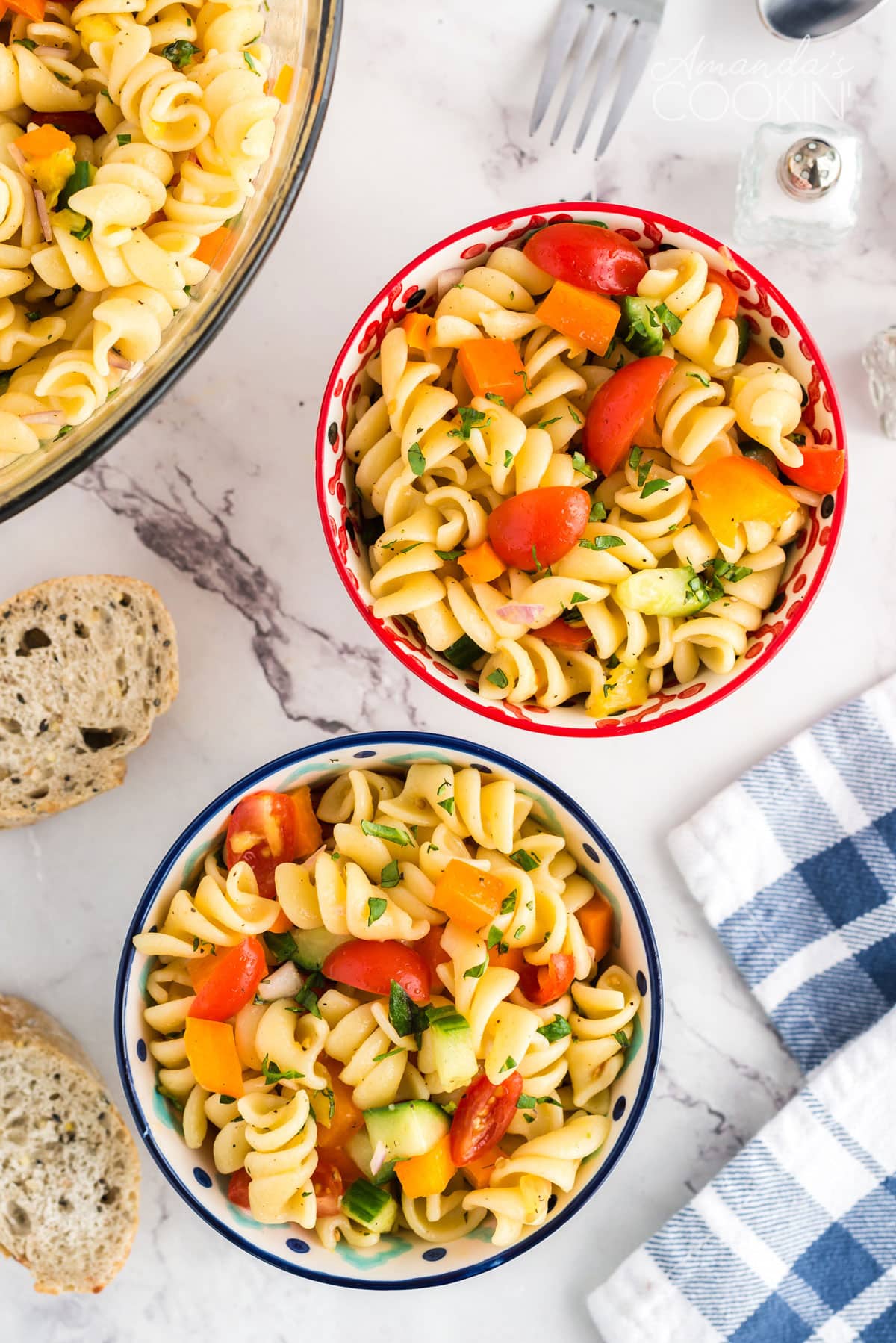 two bowls of pasta salad with a blue and white tea towel