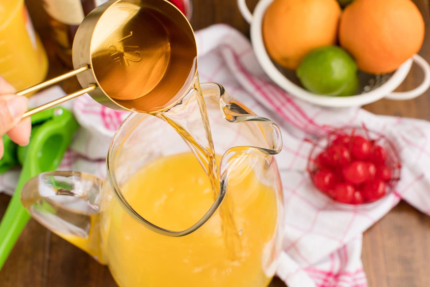 pouring rum into a pitcher of orange and pineapple juice