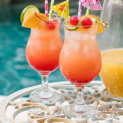 two glasses of rum punch poolside with a pitcher