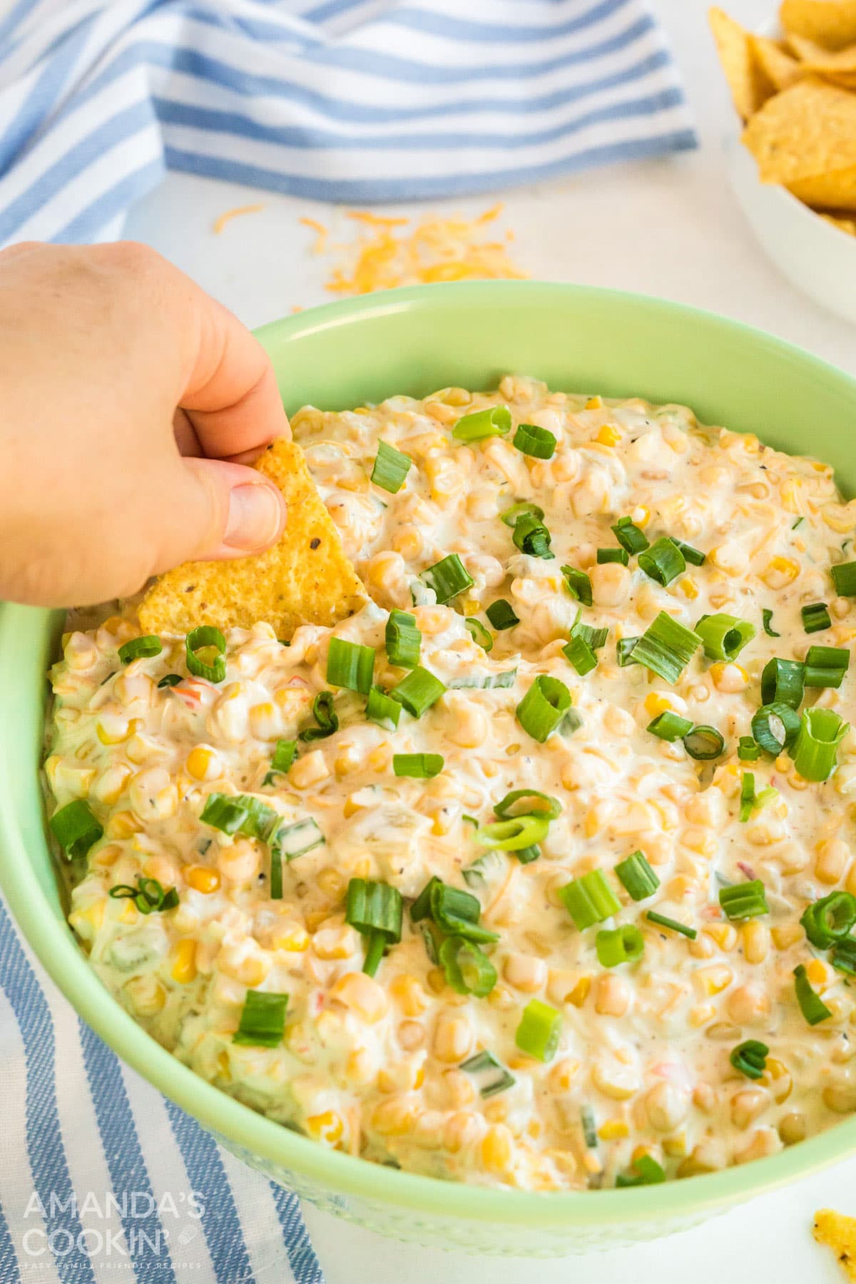 hand scooping corn dip with tortilla chip