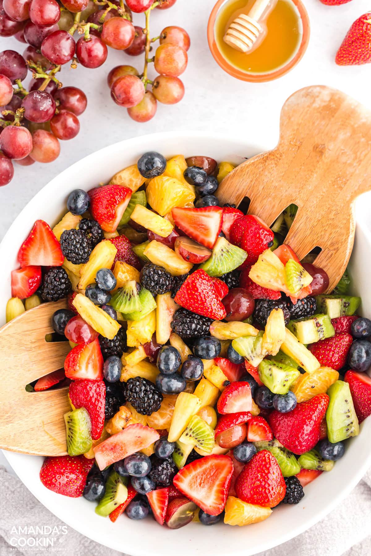 BOWL OF FRUIT SALAD WITH SERVING SPOONS