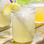 Mason jar glass of Lynchburg lemonade with a straw and lemon wedge garnish.