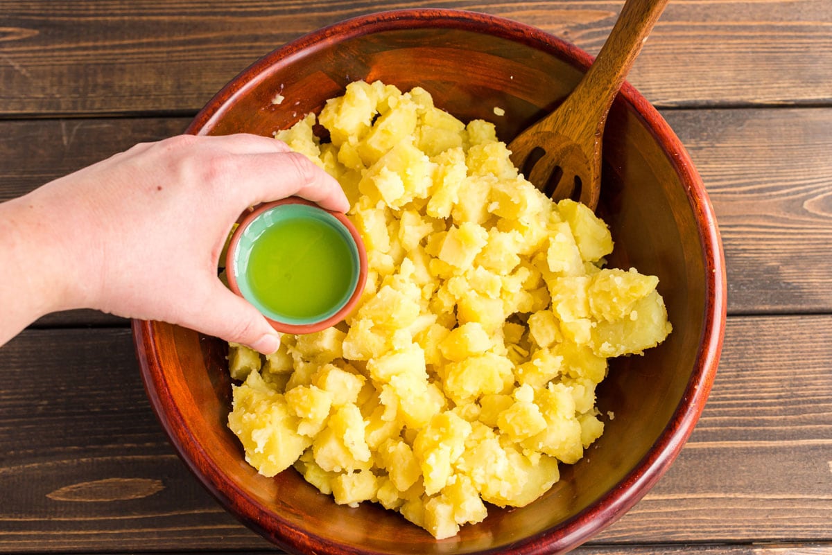 adding pickle juice to bowl of cooked potatoes