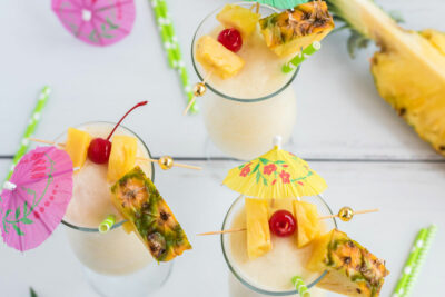 3 pina coladas with cherry and pineapple garnishes