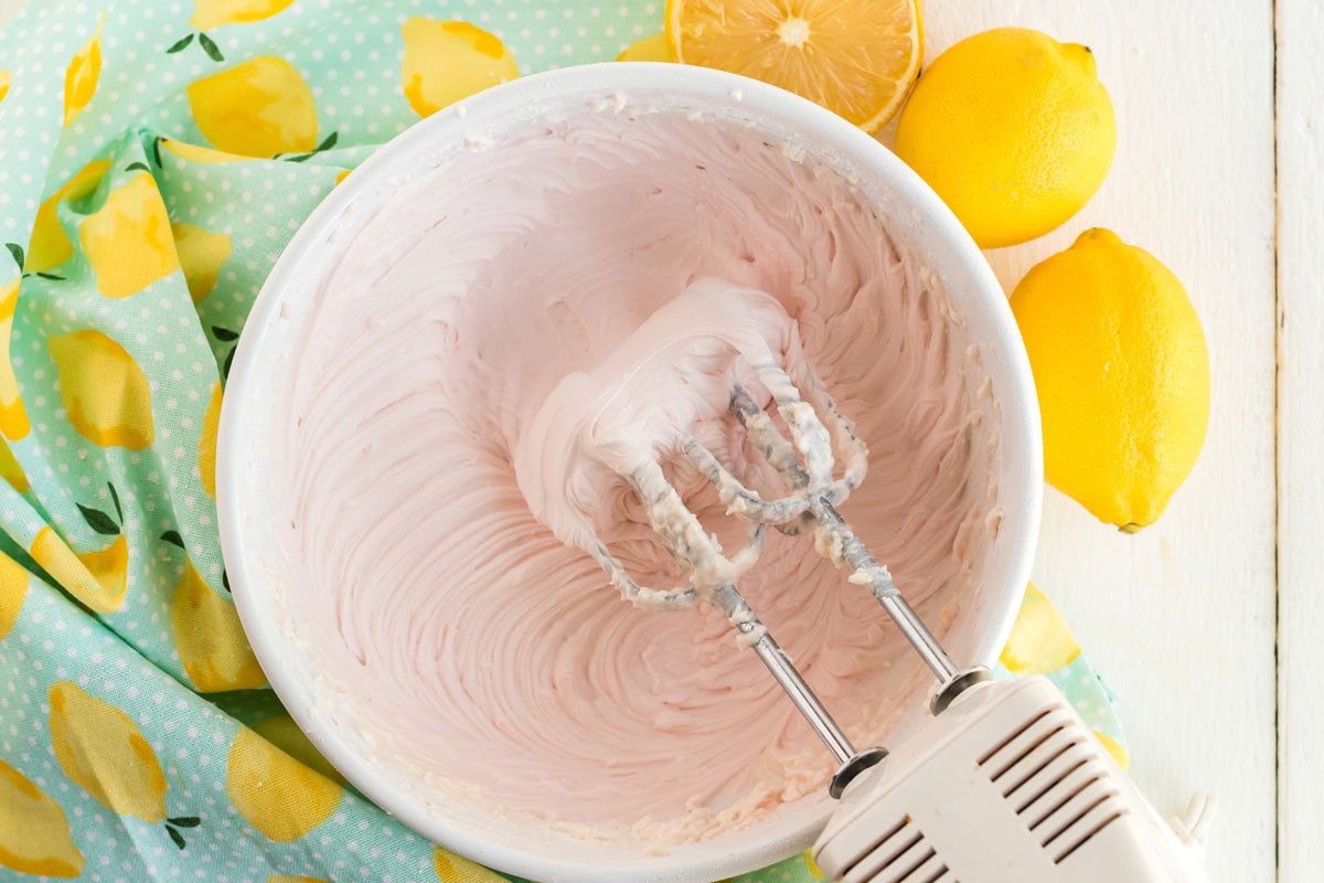 mixing pink frosting on a bowl