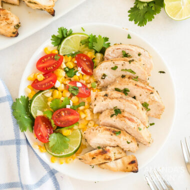 sliced cilantro lime chicken on a plate with corn and tomatoes