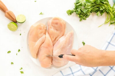 woman poking chicken breasts with a knife