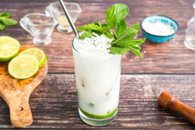 glass of coconut rum mojito garnished with mint and coconut flakes