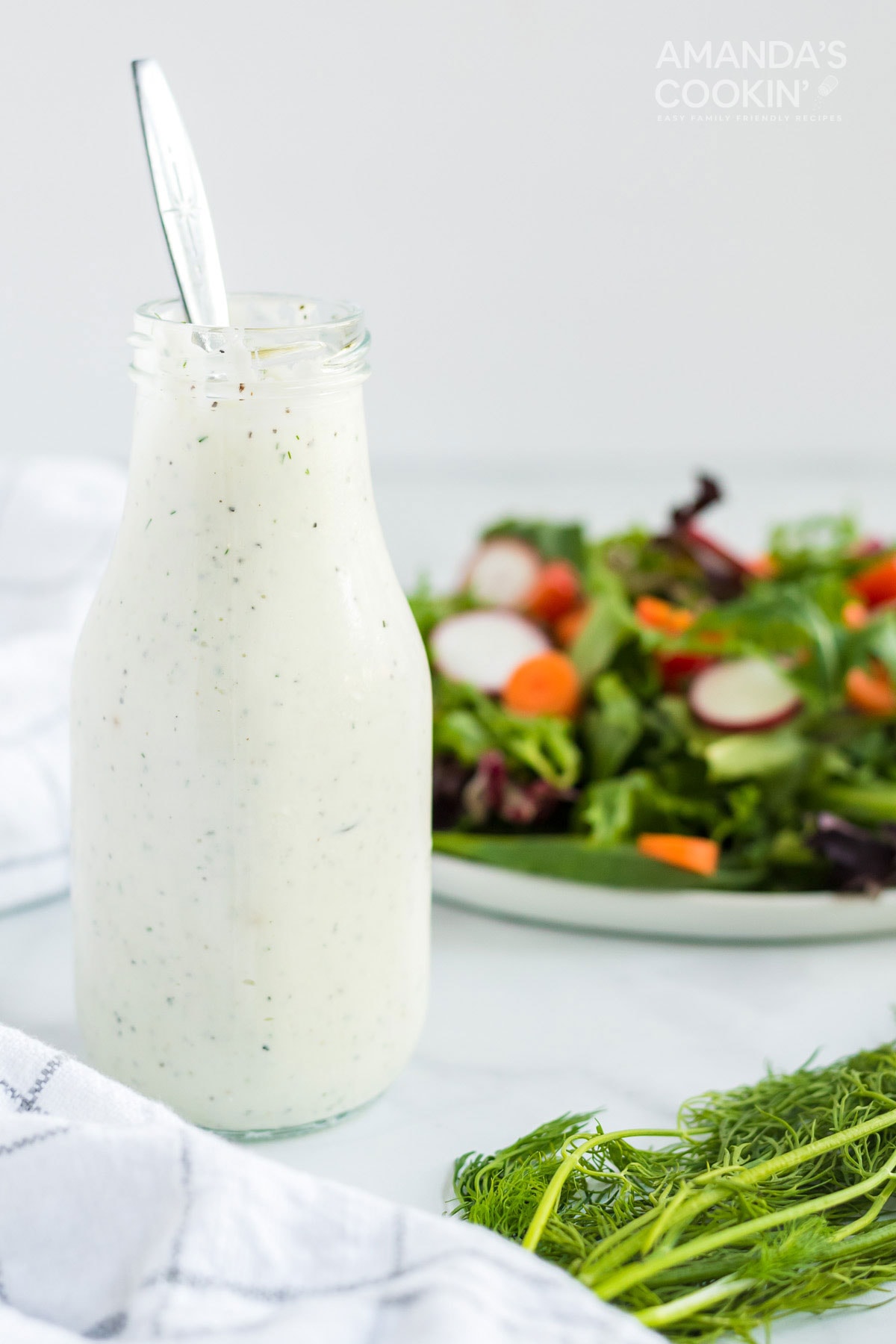 bottle of dill dressing with a spoon and salad