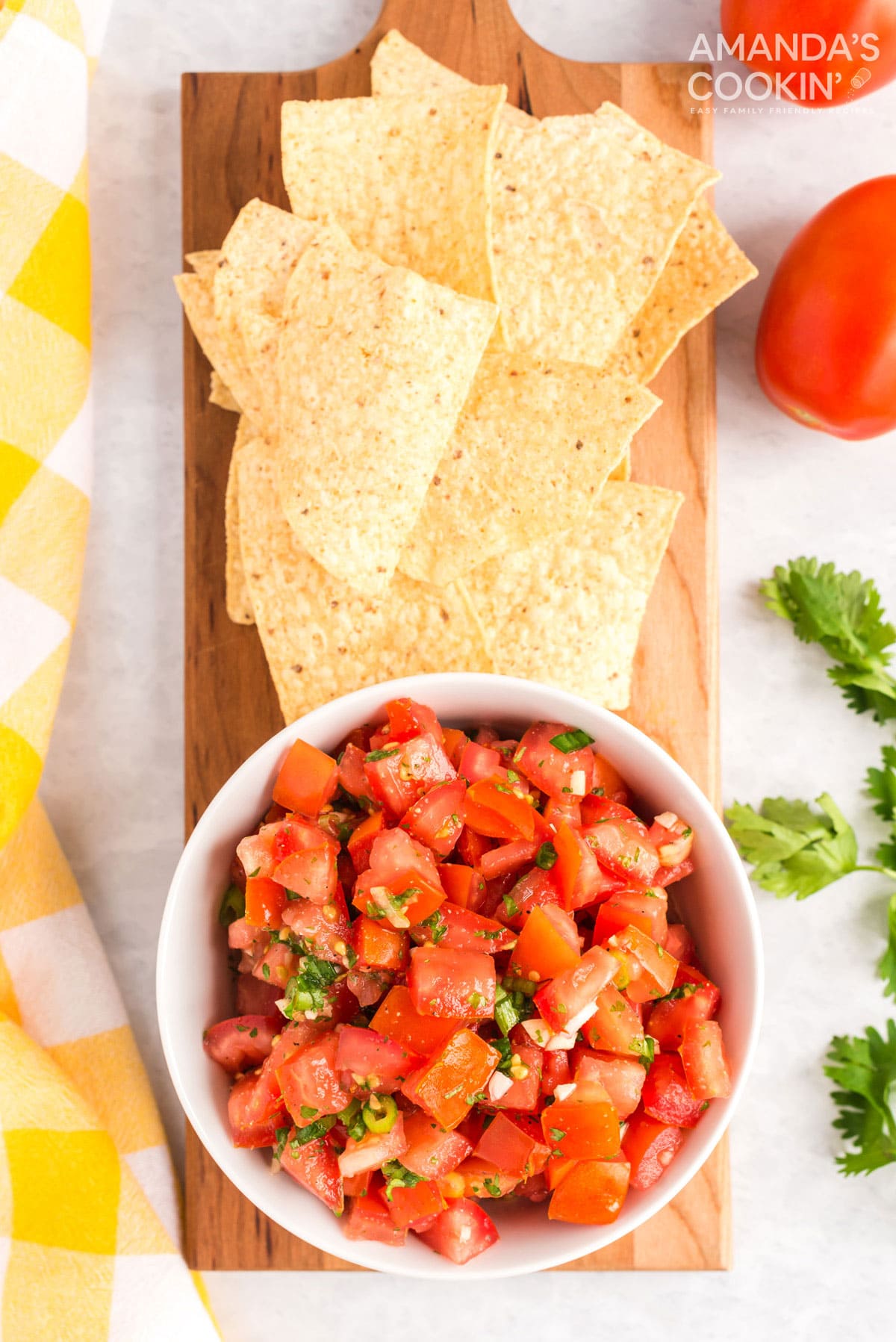 bowl of pico de gallo sitting on cutting board with tortilla chips