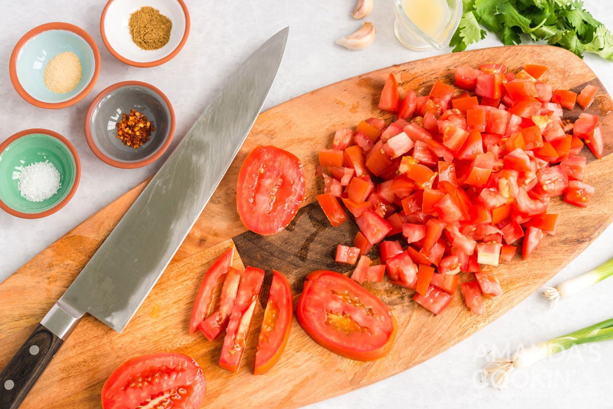 chopped tomatoes and a chefs knife on a cutting board