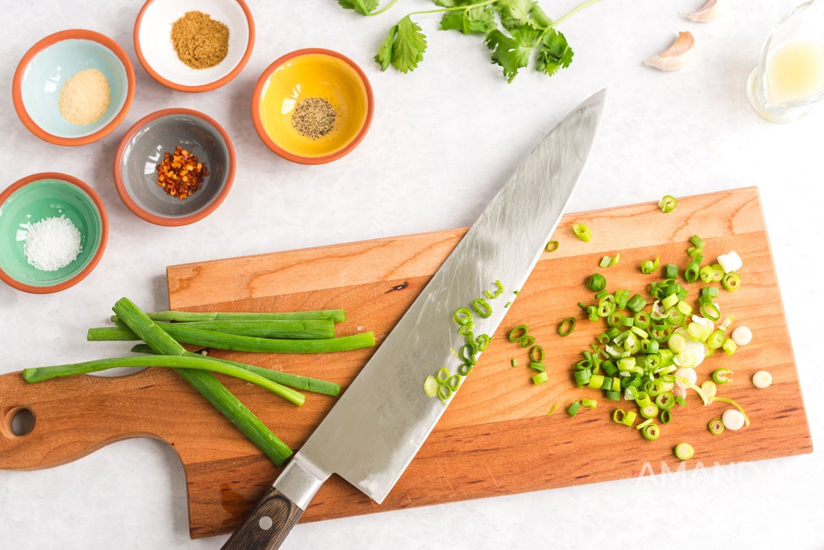 chopped green onions and a knife on cutting board