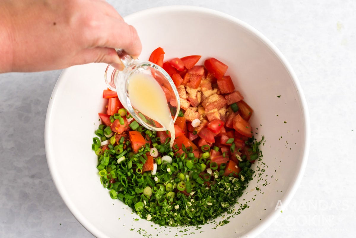adding lime juice to salsa fresca ingredients in bowl