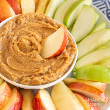bowl of peanut butter dip surrounded by apple slices