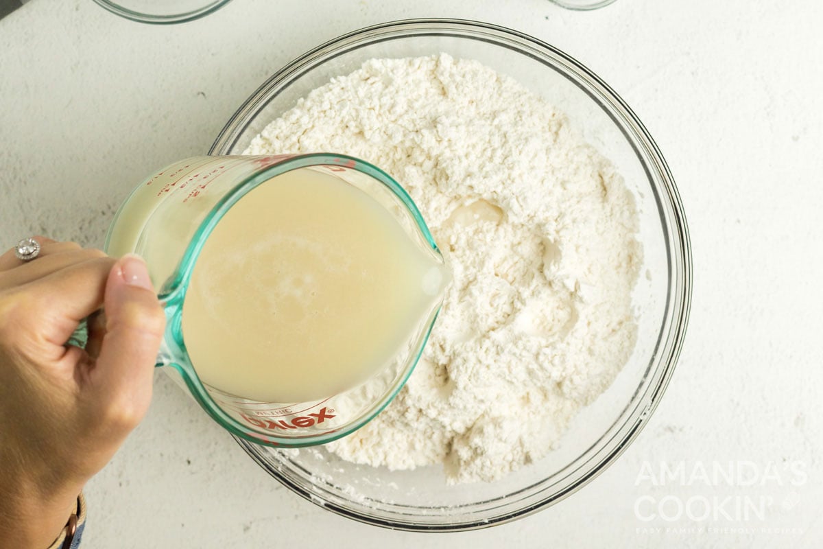 adding yeast mixture to bowl of flour