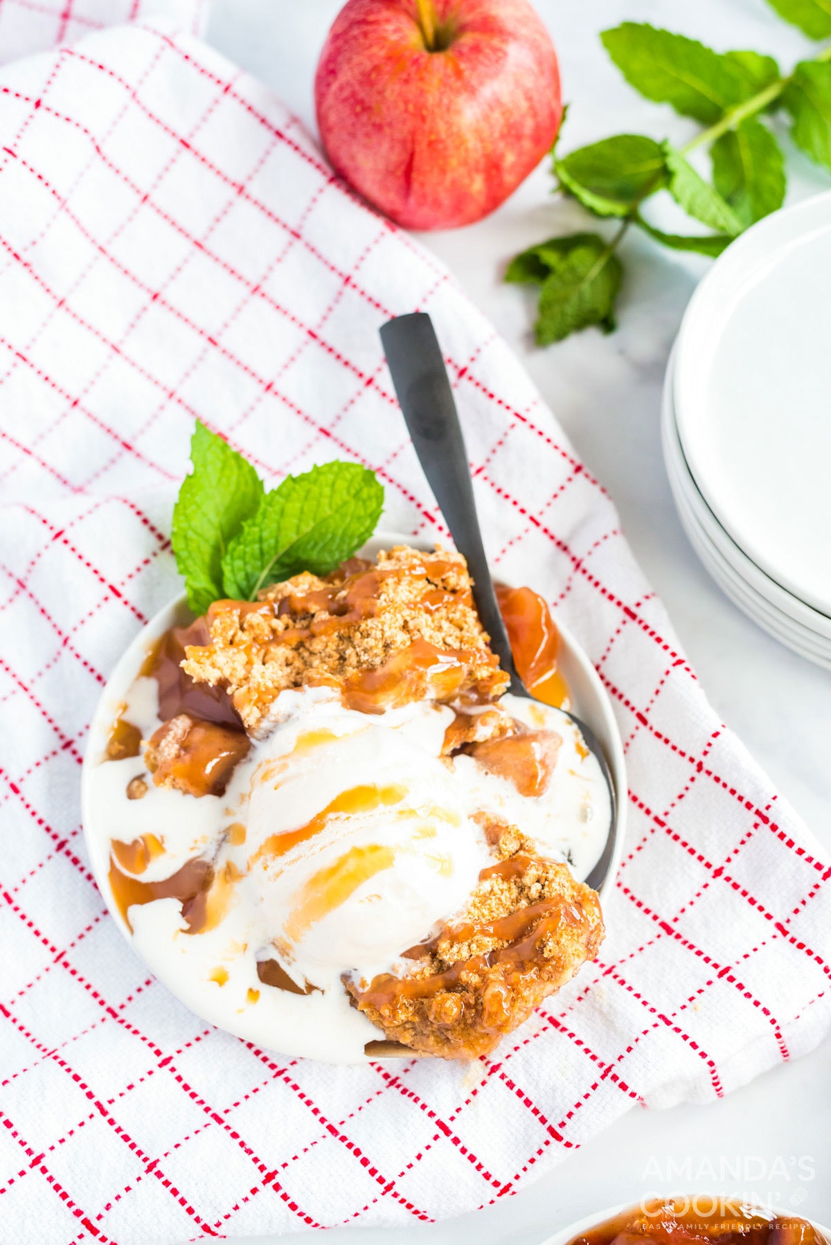 crockpot apple cobbler with ice cream on a checkered towel