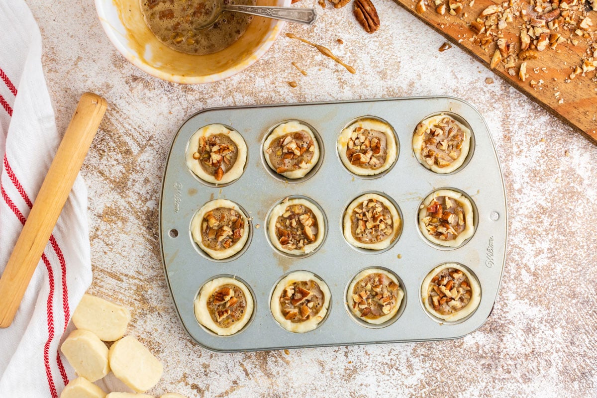 unbaked pecan tassies in a muffin tin