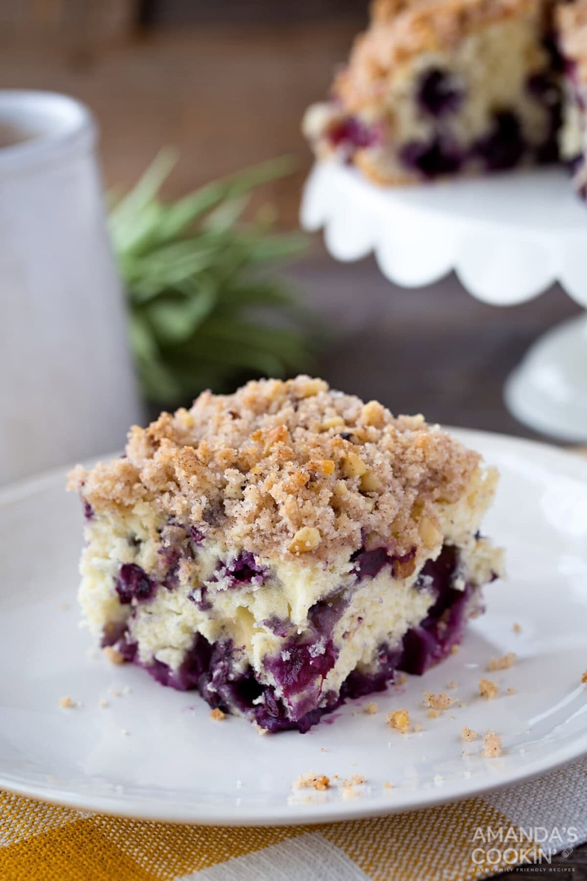 Blueberry breakfast cake, coffee cake, whatever you want to call it, it's overflowing with blueberries and absolutely delicious. #blueberrycake #blueberrycoffeecake #blueberrybuckle #blueberrydessert #blueberries #coffeecake #coffeecakerecipes #breakfastcake #recipesforblueberries slice of blueberry cake on white plate
