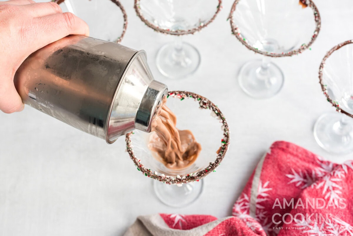 pouring shaken cocktail into martini glass