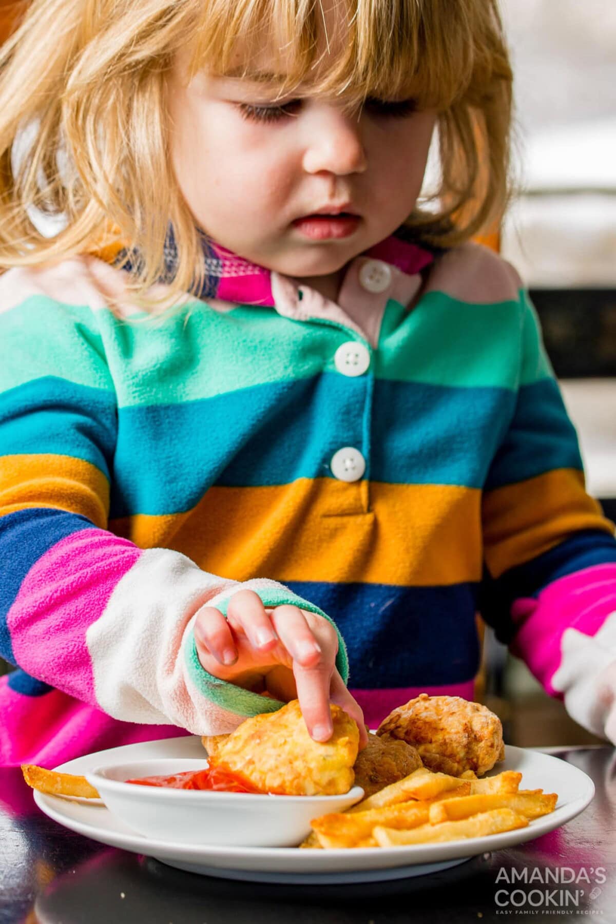 little girl dipping an air fryer chicken nugget