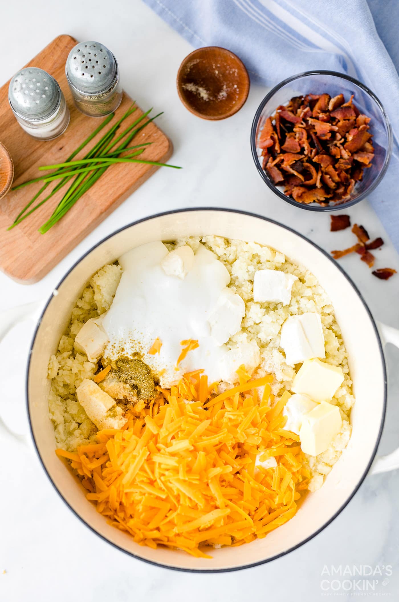 cheese and other ingredients added to potatoes in pot