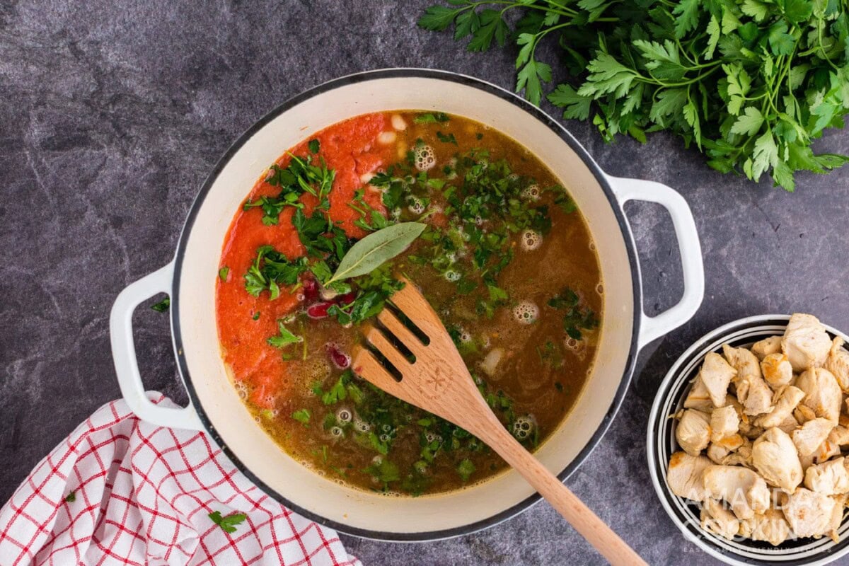 adding all ingredients into dutch oven minus the chicken and bringing to a boil