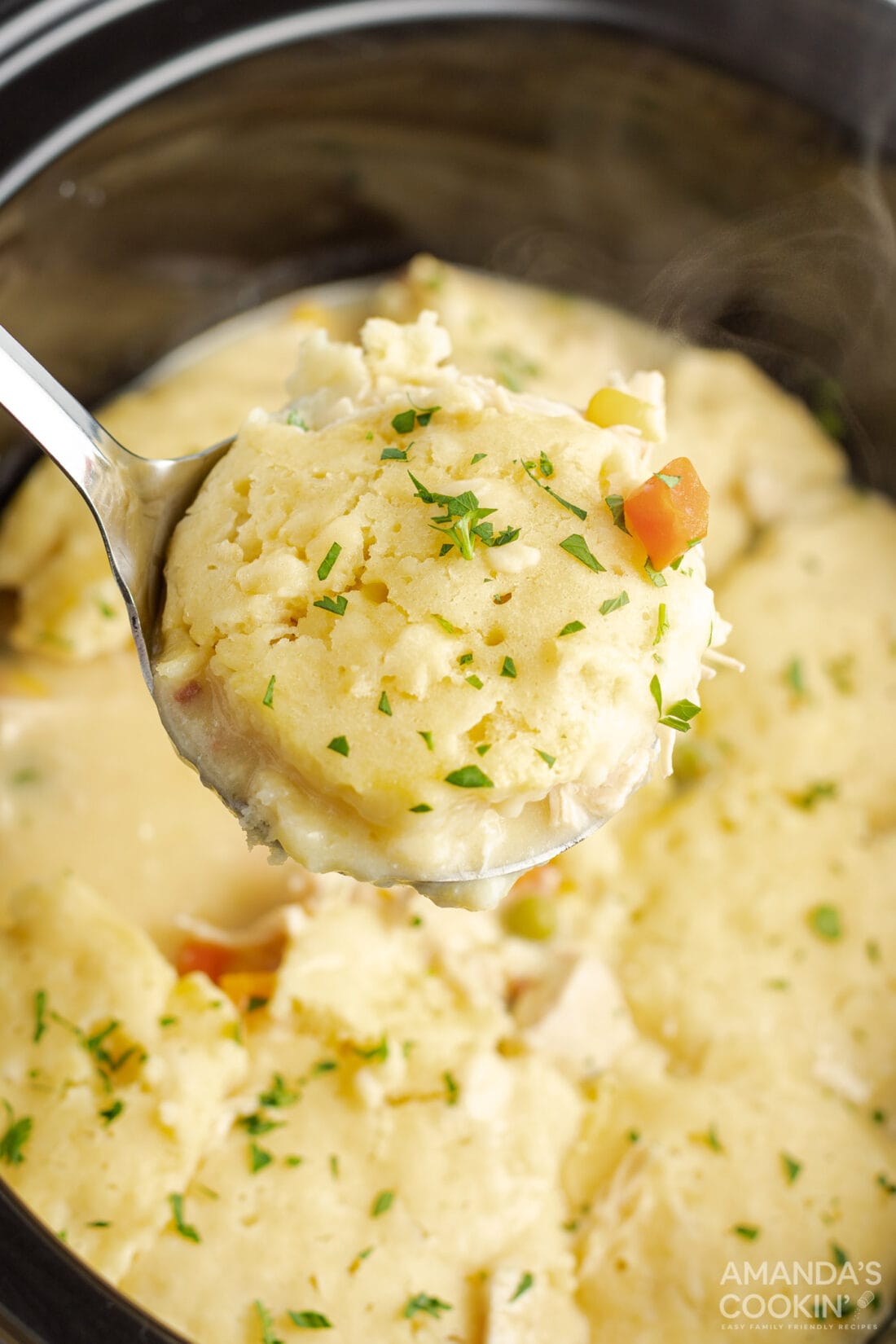 Ladle of crockpot chicken and dumplings being lifted out of the crockpot